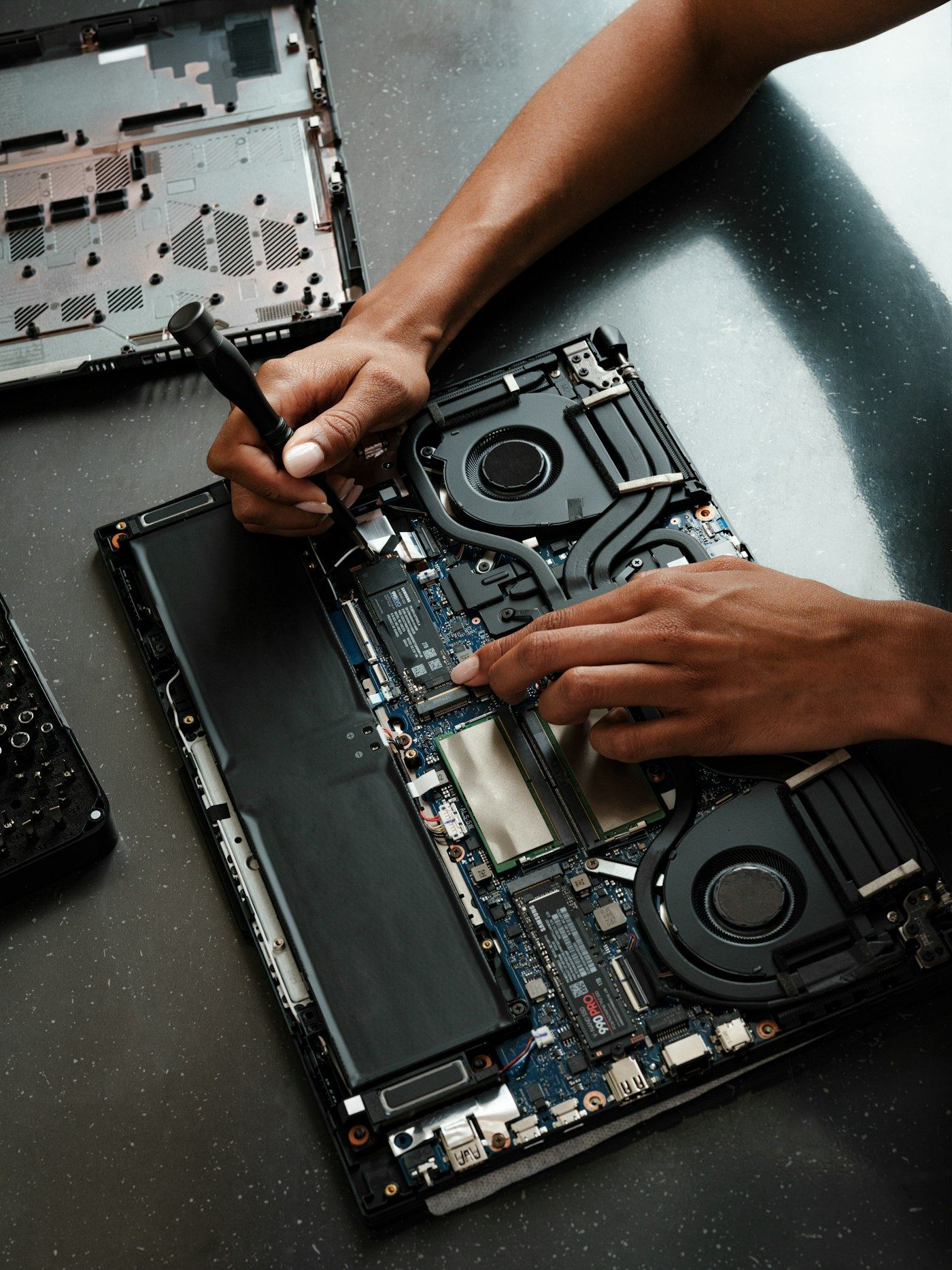 Technician repairing an open laptop with a screwdriver